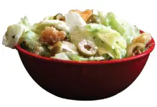 A bowl of salad with dressing on top.