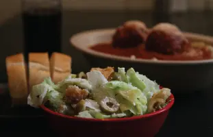 A bowl of salad and two plates with food.